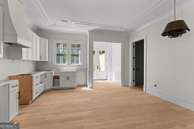 1111 Swift Crk, Greensboro, GA 30642 - kitchen featuring premium range hood, ornamental molding, light wood-style floors, white cabinets, and a raised ceiling