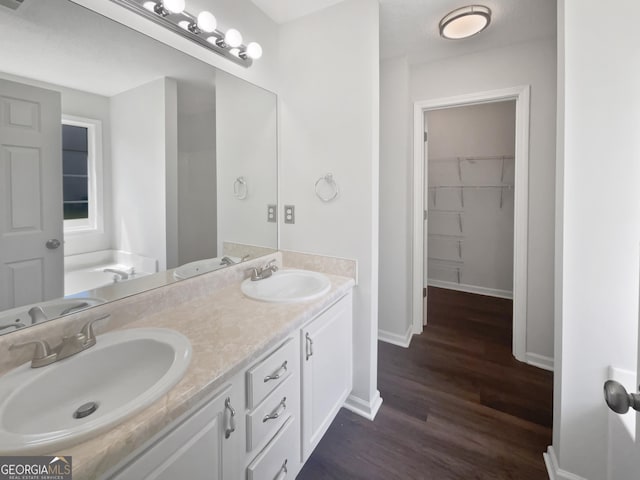 4335 Northwind Dr, Ellenwood, GA 30294 - full bathroom with wood finished floors, baseboards, double vanity, a walk in closet, and a garden tub