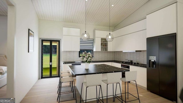 LL14 Coffey Ln, Young Harris, GA 30582 - kitchen with black fridge with ice dispenser, dark countertops, white cabinets, a kitchen breakfast bar, and decorative backsplash