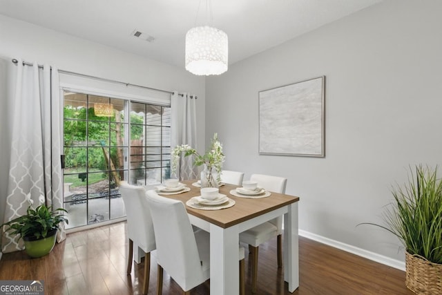 dining room with wood finished floors, a chandelier, and baseboards