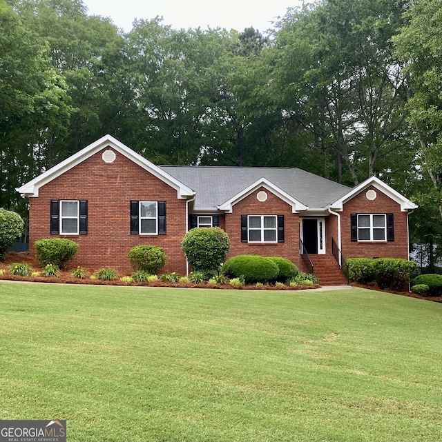 ranch-style house with brick siding, a front lawn, and view of scattered trees