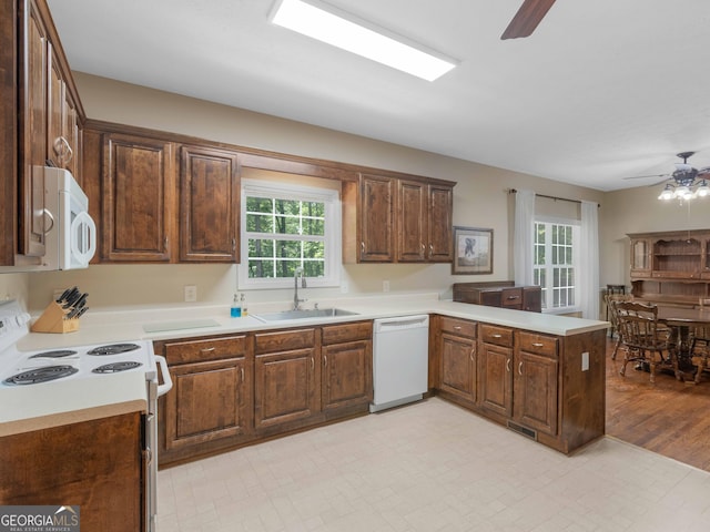 kitchen with white appliances, a sink, a ceiling fan, a peninsula, and plenty of natural light