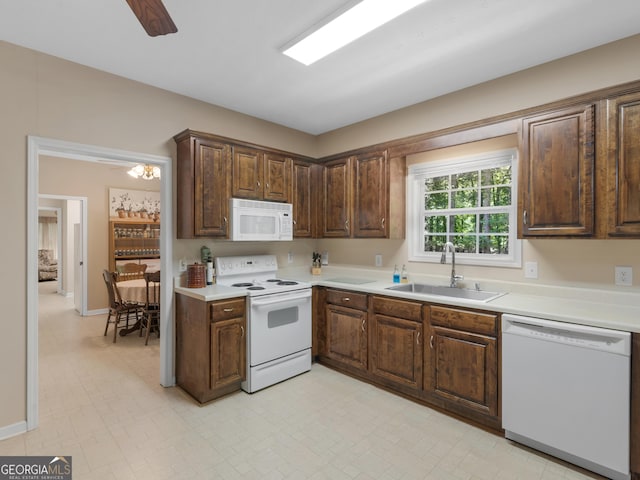 kitchen with white appliances, a sink, light countertops, dark brown cabinetry, and baseboards