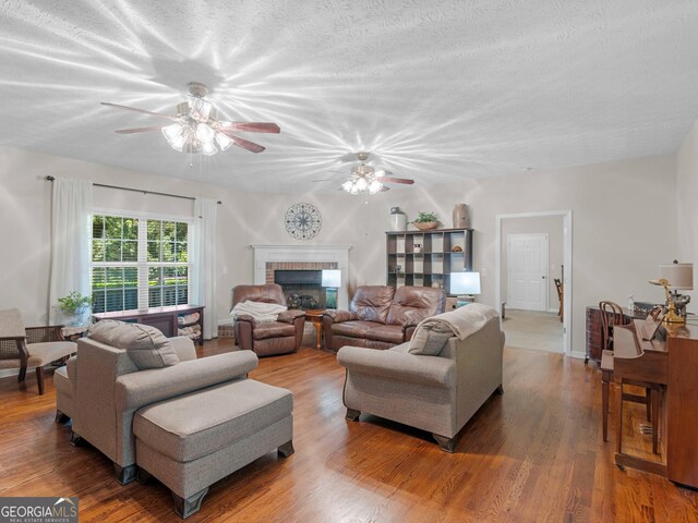 175 N Unity Grove Rd, Locust Grove, GA 30248 - living room featuring a ceiling fan, wood finished floors, a brick fireplace, and a textured ceiling