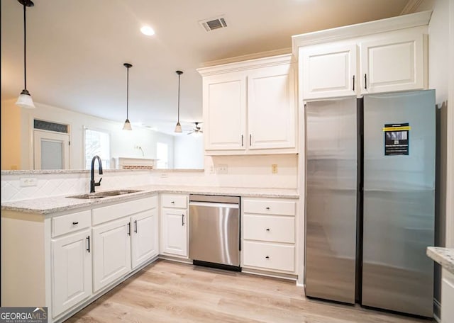 21 Whitegrass Way, Grayson, GA 30017 - kitchen featuring appliances with stainless steel finishes, a sink, white cabinetry, a peninsula, and light wood-type flooring
