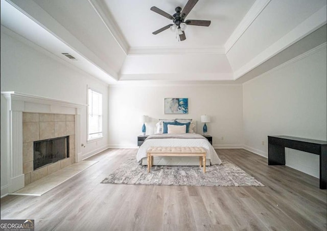 21 Whitegrass Way, Grayson, GA 30017 - bedroom featuring a tray ceiling, wood finished floors, a tiled fireplace, ornamental molding, and ceiling fan