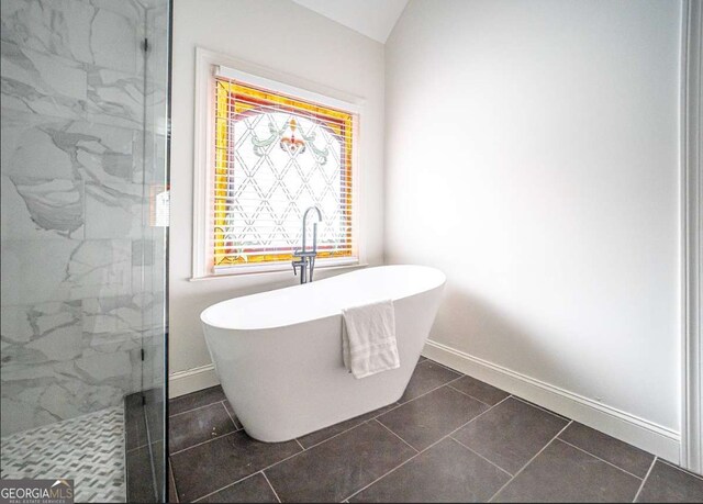 21 Whitegrass Way, Grayson, GA 30017 - bathroom featuring a marble finish shower, a soaking tub, baseboards, lofted ceiling, and tile patterned floors