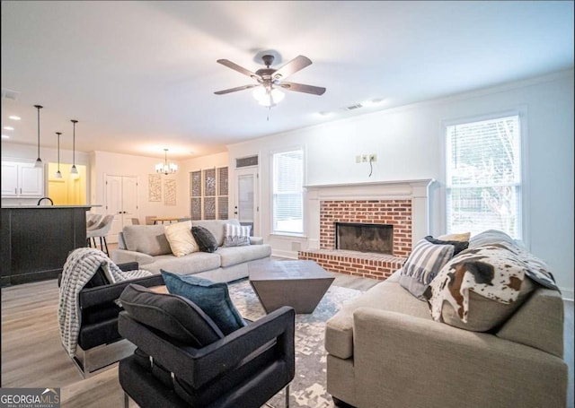 21 Whitegrass Way, Grayson, GA 30017 - living area featuring light wood finished floors, a chandelier, ceiling fan, a brick fireplace, and ornamental molding