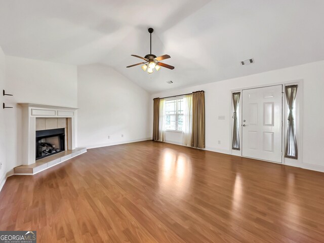 unfurnished living room with a ceiling fan, wood finished floors, lofted ceiling, a fireplace, and baseboards