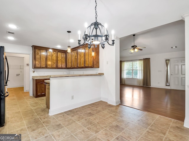 kitchen featuring a peninsula, ceiling fan, open floor plan, a chandelier, and brown cabinetry