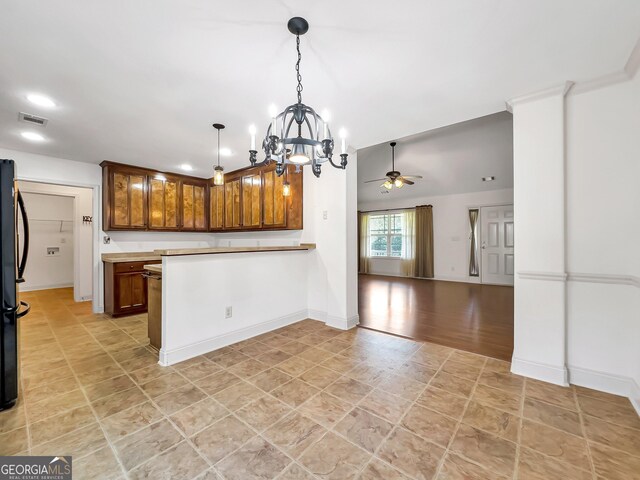 kitchen featuring a ceiling fan, a peninsula, open floor plan, pendant lighting, and a chandelier