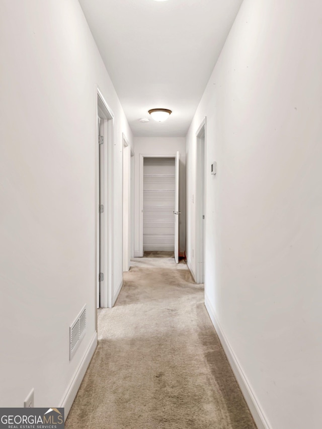 hall featuring light carpet and baseboards