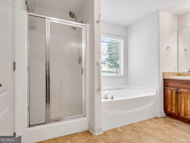 full bathroom featuring a shower stall, vanity, a garden tub, and baseboards