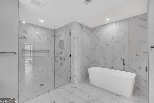 bathroom with marble tiled flooring, a marble finish shower, a freestanding tub, and recessed lighting