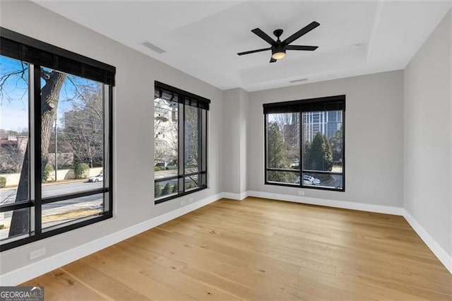 empty room featuring wood finished floors, plenty of natural light, and baseboards