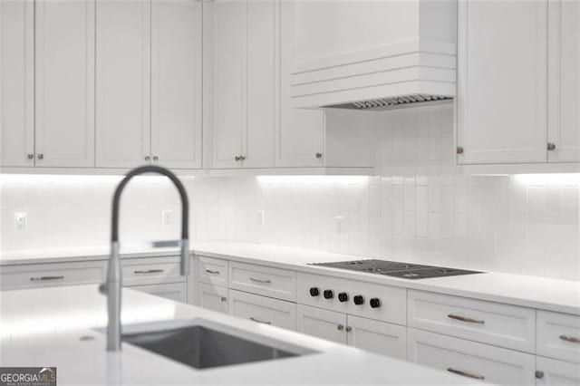 kitchen featuring backsplash, custom range hood, light countertops, and white cabinets
