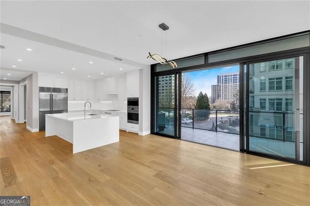 kitchen with double oven, white cabinetry, light wood finished floors, and recessed lighting