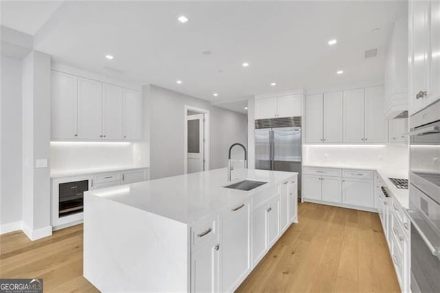 kitchen featuring a sink, light wood finished floors, white cabinets, and recessed lighting