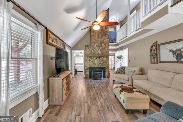 living room with a ceiling fan, high vaulted ceiling, wood finished floors, and baseboards