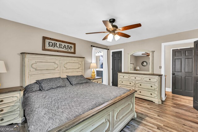 bedroom with wood finished floors, a ceiling fan, and baseboards