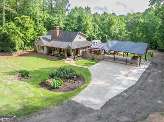 view of front of property featuring covered porch, a front yard, driveway, a chimney, and a carport