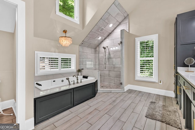 bathroom with vaulted ceiling, wood finished floors, a stall shower, baseboards, and a bath