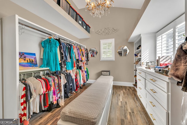 spacious closet with a chandelier, wood finished floors, and a high ceiling