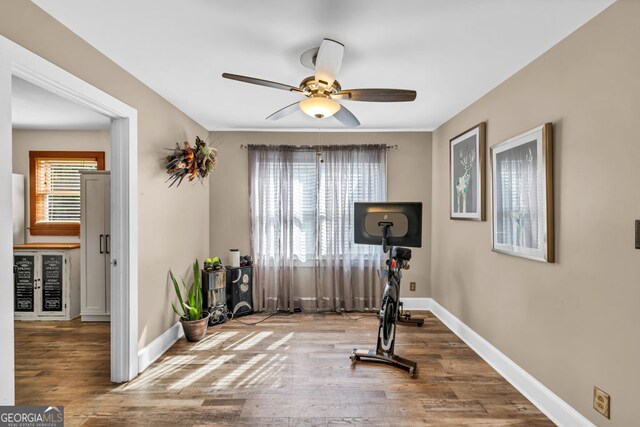 workout room featuring a ceiling fan, wood finished floors, and baseboards
