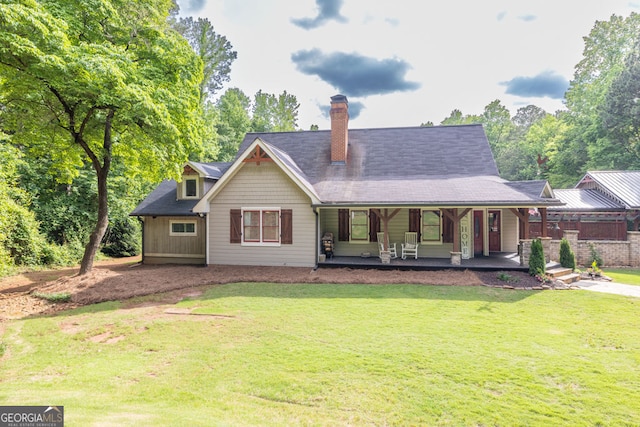 rear view of property with a lawn, a chimney, and a porch
