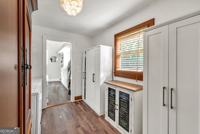 hall with washing machine and clothes dryer, wood finished floors, a chandelier, baseboards, and wine cooler