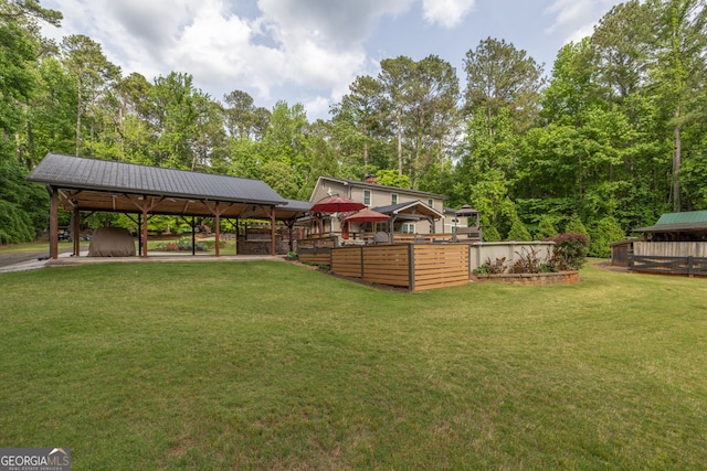 view of grassy yard with a gazebo and view of wooded area