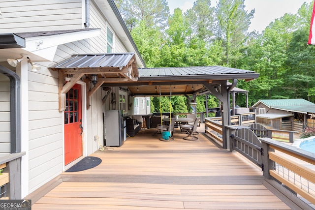 deck featuring outdoor dining space and view of wooded area