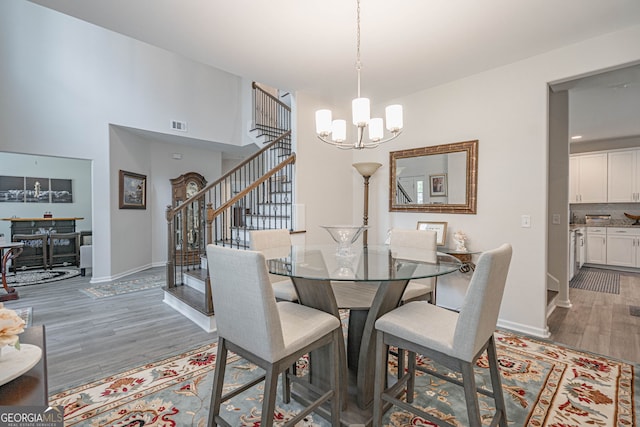 dining space with stairway, light wood-style flooring, a chandelier, and baseboards