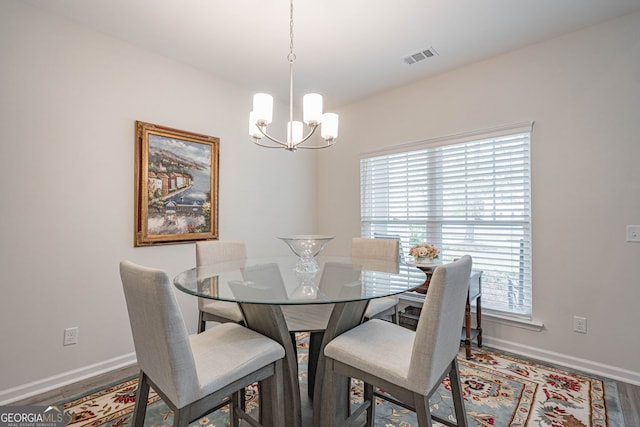 dining space featuring a chandelier, baseboards, and wood finished floors