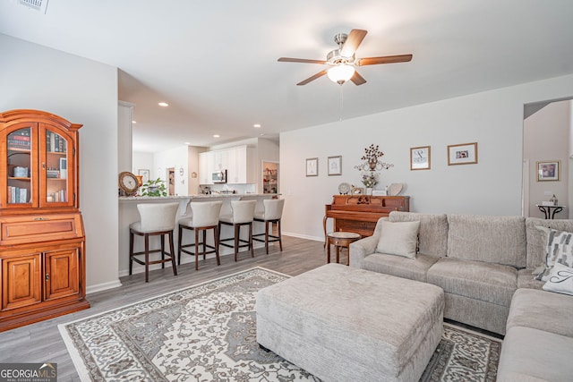 living room featuring a ceiling fan, light wood finished floors, recessed lighting, and baseboards