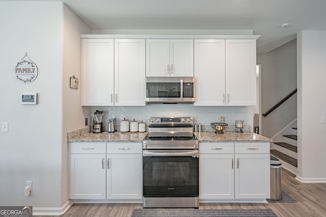 kitchen featuring stainless steel appliances, light wood-style flooring, white cabinetry, and tasteful backsplash