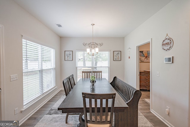 dining room with dark wood-type flooring, a chandelier, and baseboards