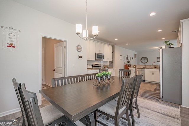 dining area with light wood finished floors, recessed lighting, a chandelier, and baseboards