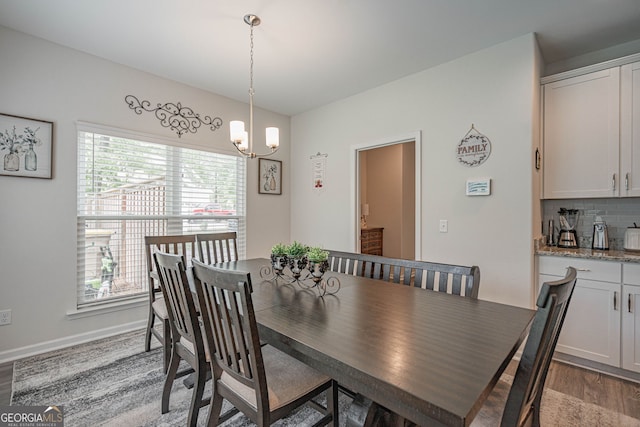 dining area with wood finished floors, a chandelier, and baseboards