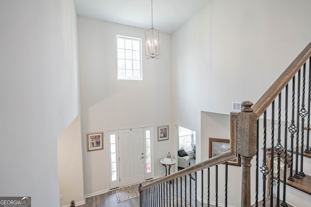 foyer entrance featuring a chandelier, wood finished floors, a high ceiling, stairs, and baseboards