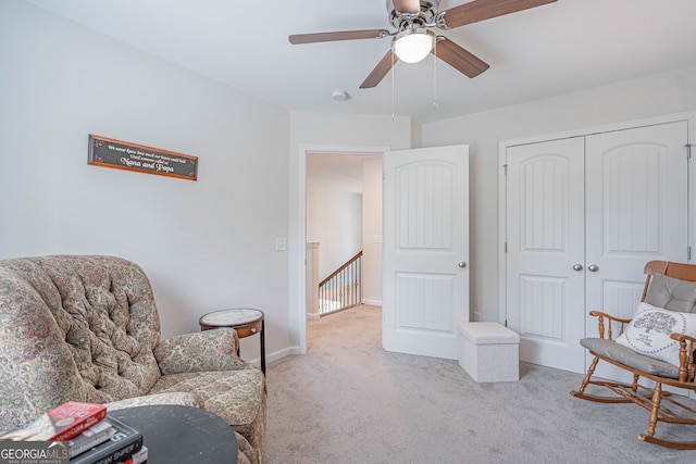 sitting room with carpet floors, an upstairs landing, and ceiling fan