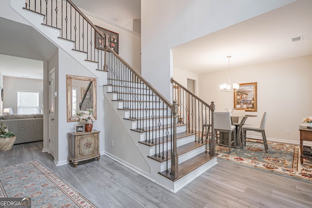 staircase featuring wood finished floors, a chandelier, and baseboards