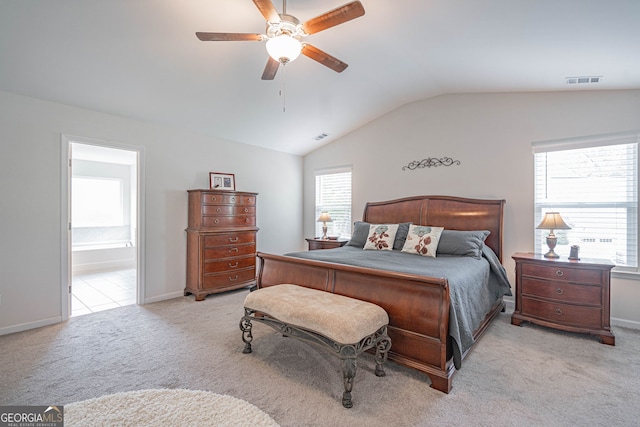 bedroom with lofted ceiling, light colored carpet, ensuite bath, ceiling fan, and baseboards