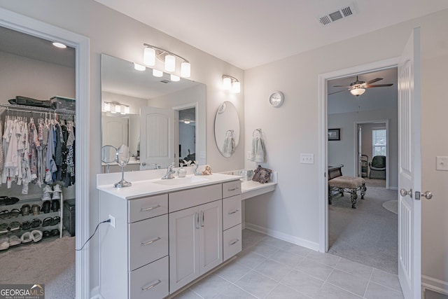 full bathroom featuring tile patterned floors, vanity, a walk in closet, a ceiling fan, and baseboards