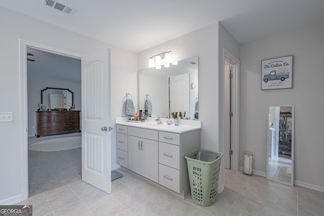 bathroom with tile patterned floors, vanity, baseboards, and a spacious closet