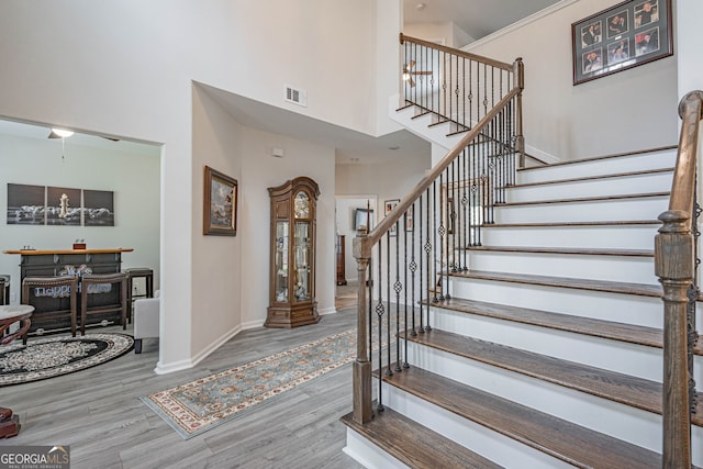 stairway with a towering ceiling, wood finished floors, and baseboards