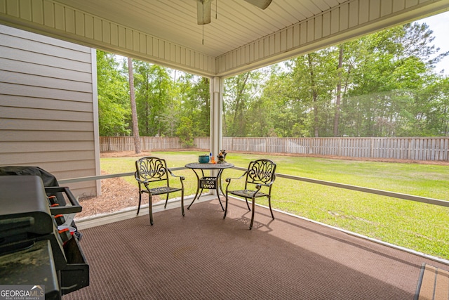 sunroom / solarium featuring ceiling fan, view of scattered trees, and plenty of natural light