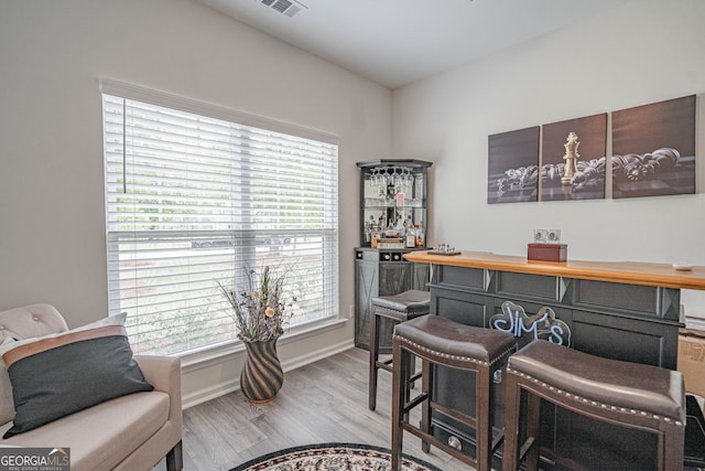 office featuring a dry bar, light wood-style floors, and baseboards