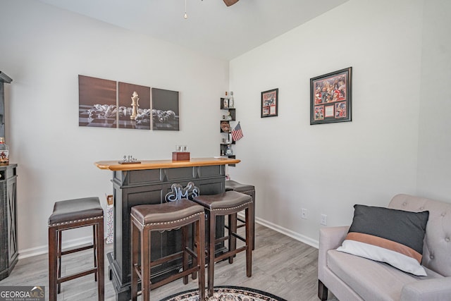 office area with light wood-type flooring, a dry bar, baseboards, and a ceiling fan