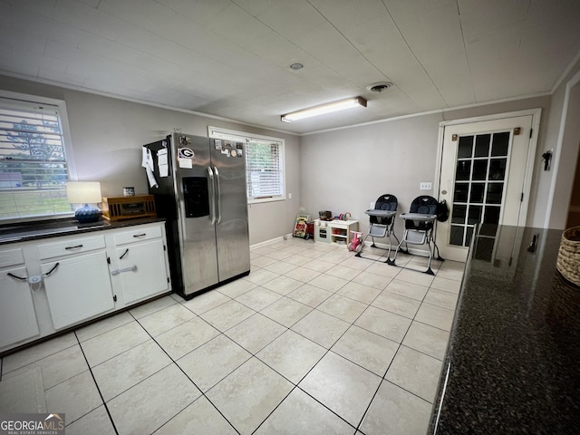 kitchen featuring stainless steel refrigerator with ice dispenser, white cabinetry, light tile patterned floors, and ornamental molding